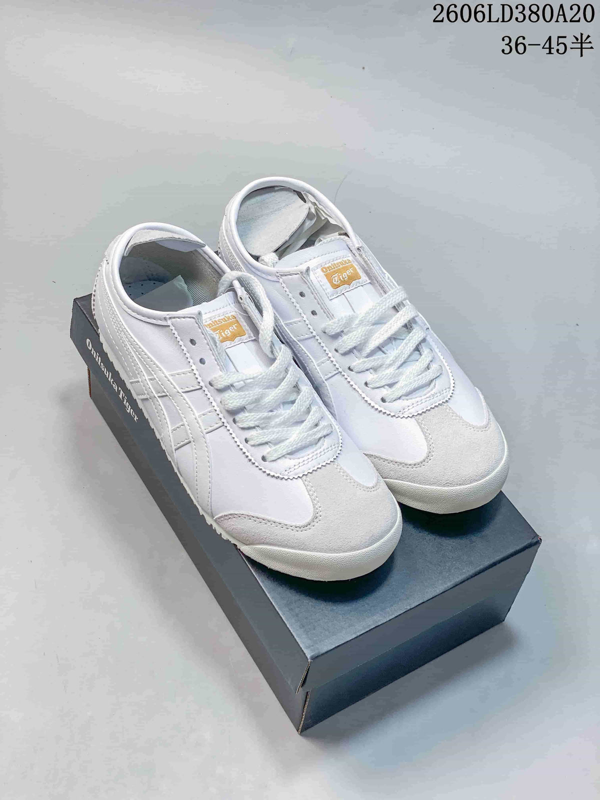Pair of white low-top sneakers with white side stripes, displayed on a shoe box.