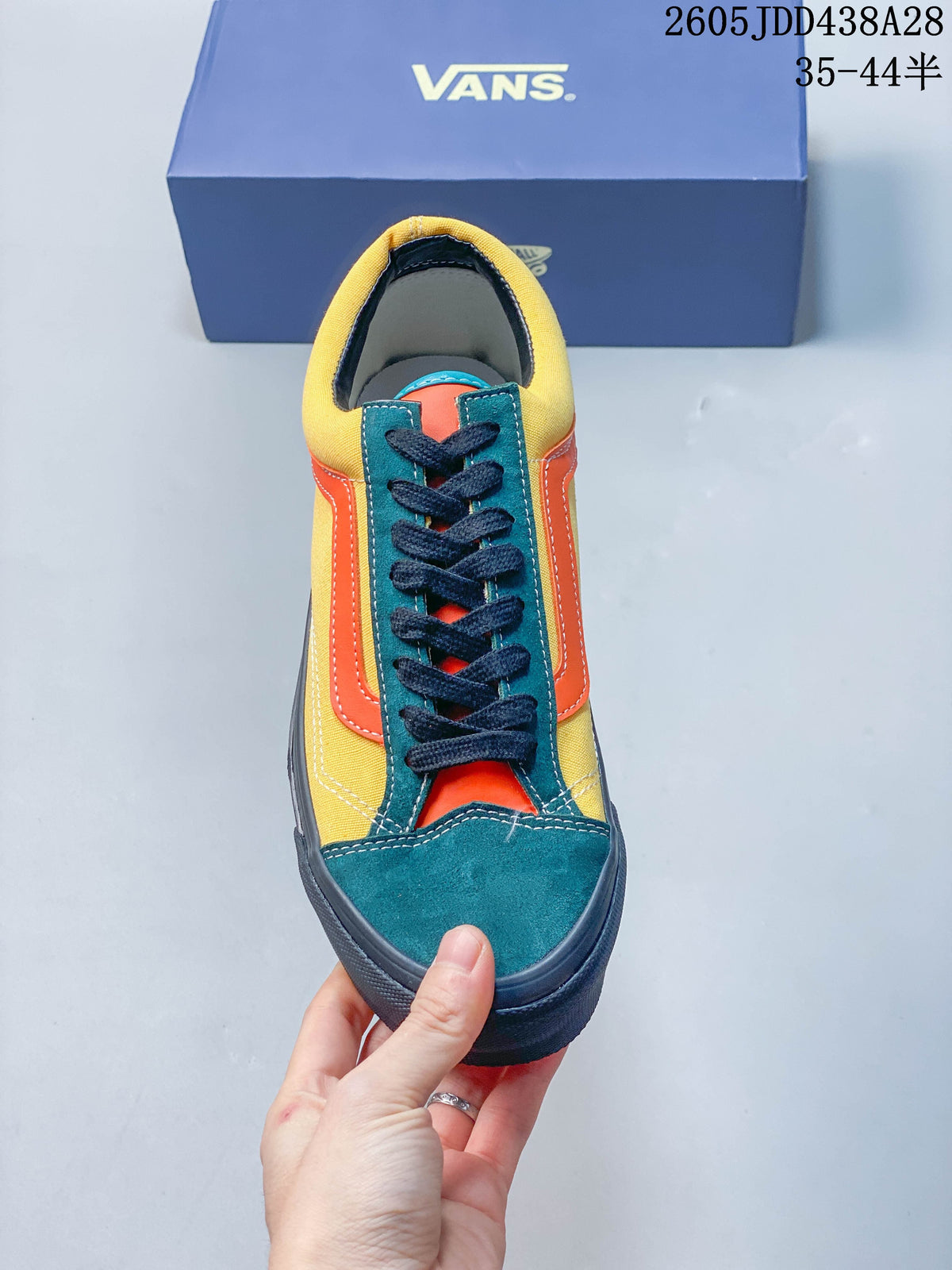 Front view of the sneaker showing its teal toe, orange tongue panel, and dark laces