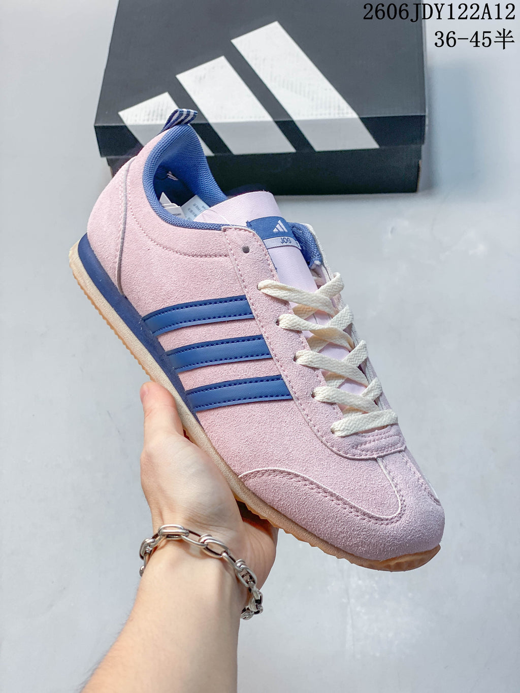 Angled side view of the pink sneaker with blue stripes and cream laces