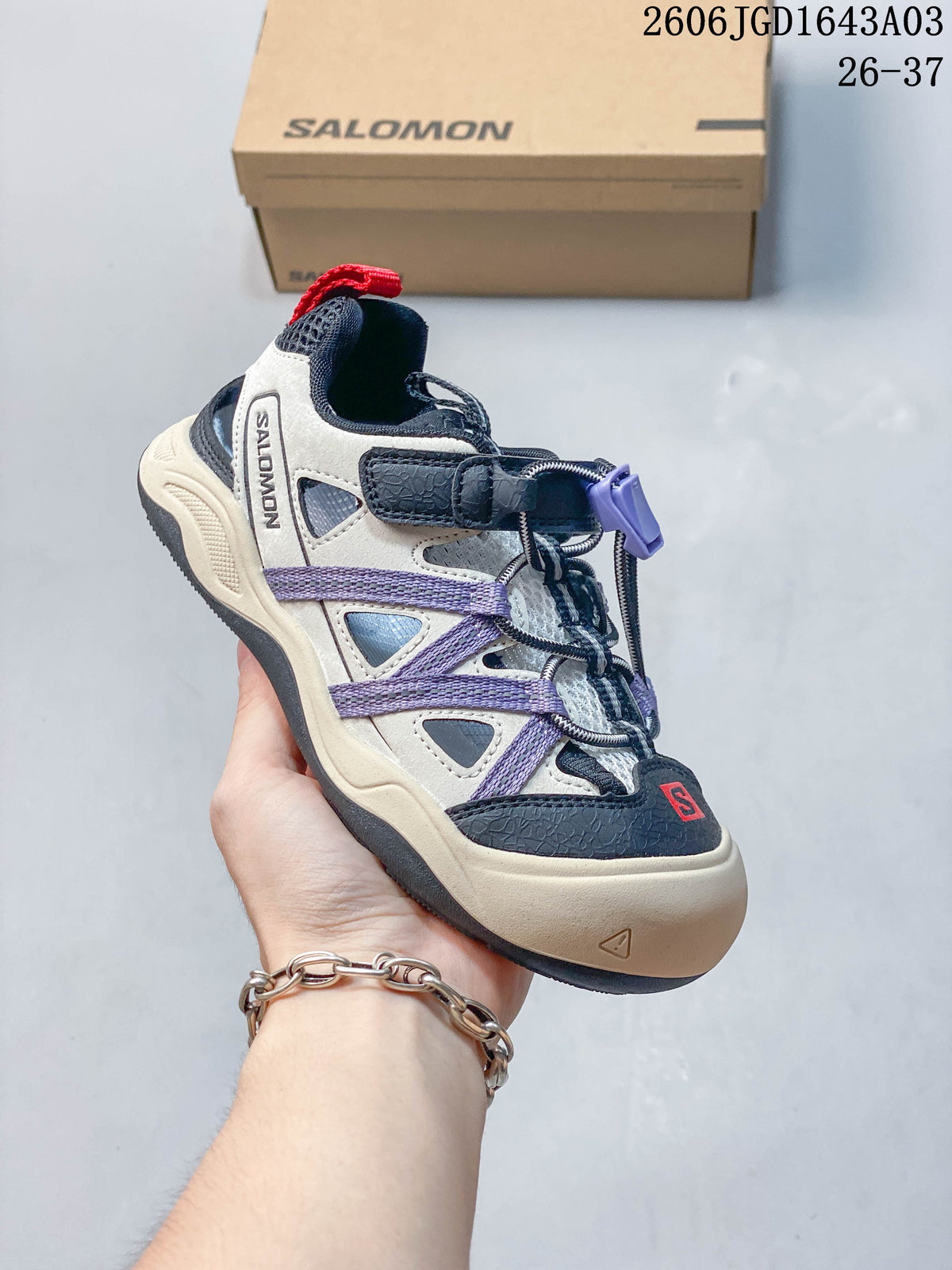 Side view of a cream, navy, and lavender Salomon kids' sneaker
