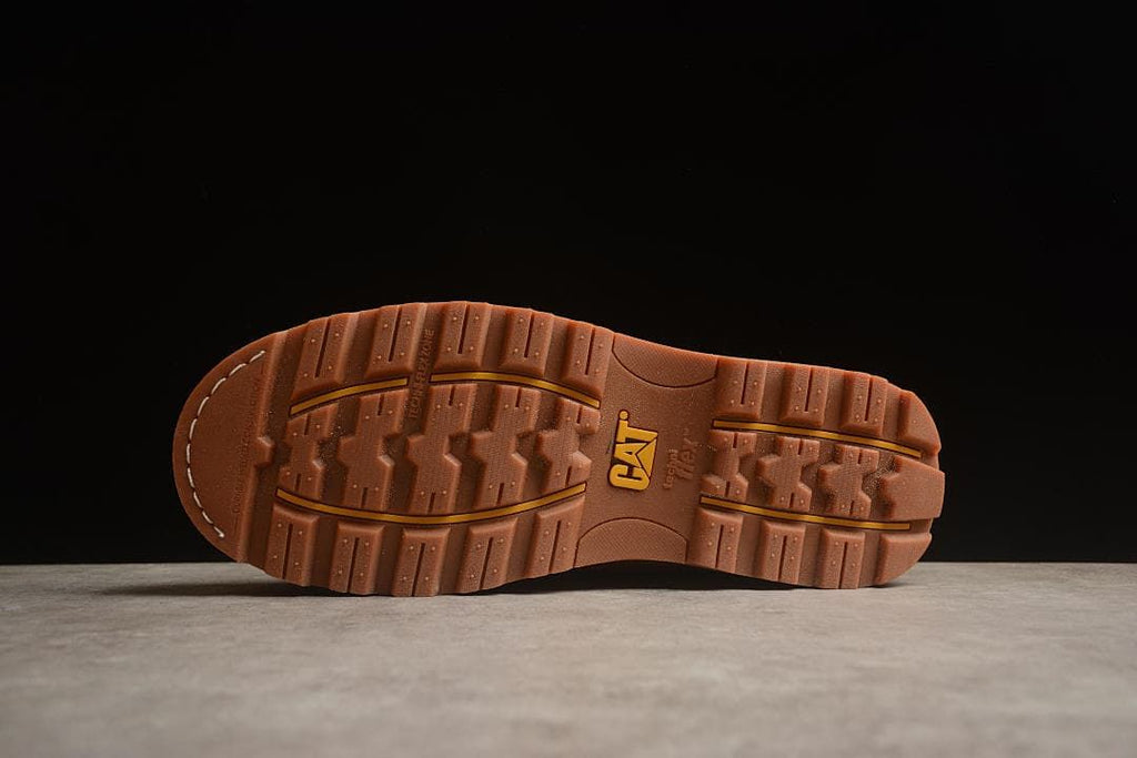 Underside of the shoe showing its lugged brown tread
