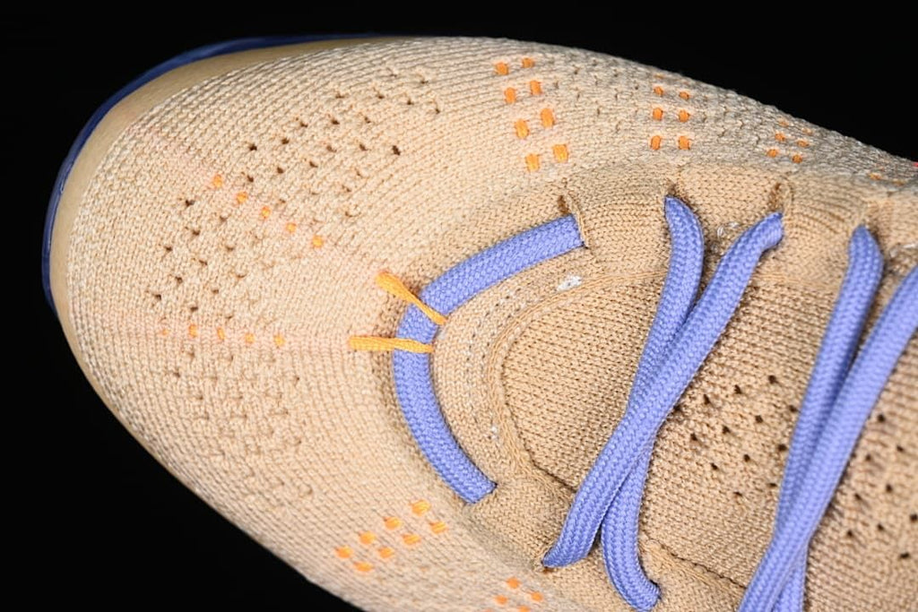 Close-up of the knit toe box with orange accents and lavender laces.