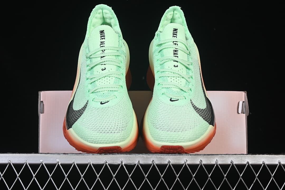 Front view of the pair showing the mint-green uppers and coral-orange soles.