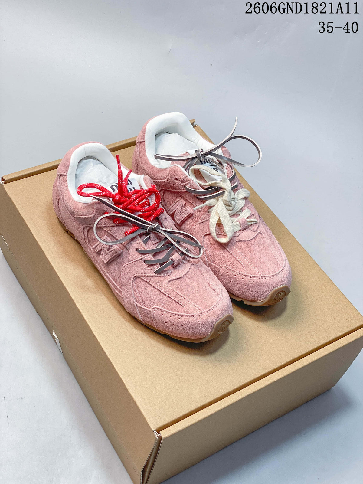 Pair of pink New Balance-style low-top sneakers with contrasting laces, shown on a box