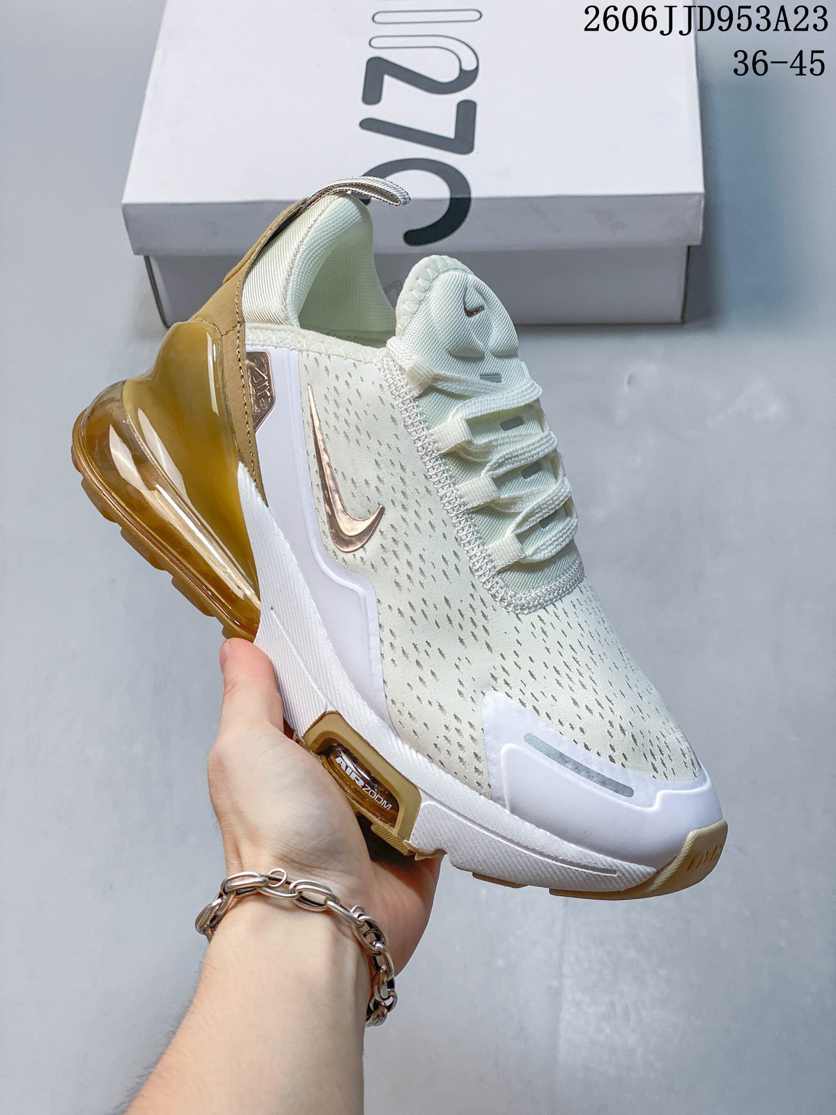 Side view of a white Nike Air Max 270 sneaker with gold-toned accents.