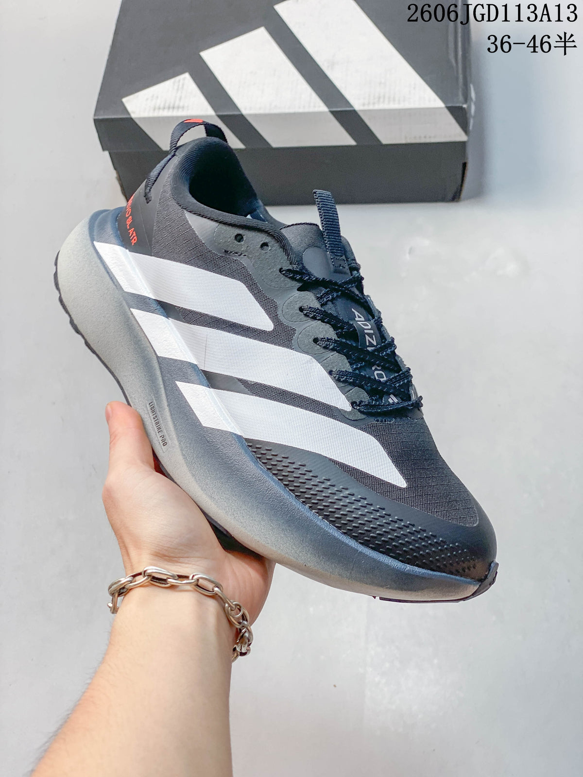 Side view of the shoe showing its white stripes, gray midsole, and charcoal upper.