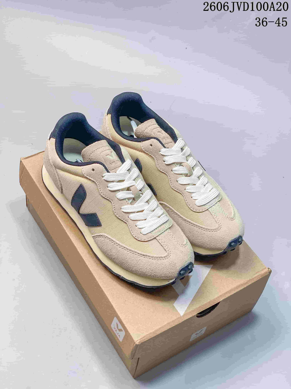 Beige low-top sneakers with navy side logos and white laces