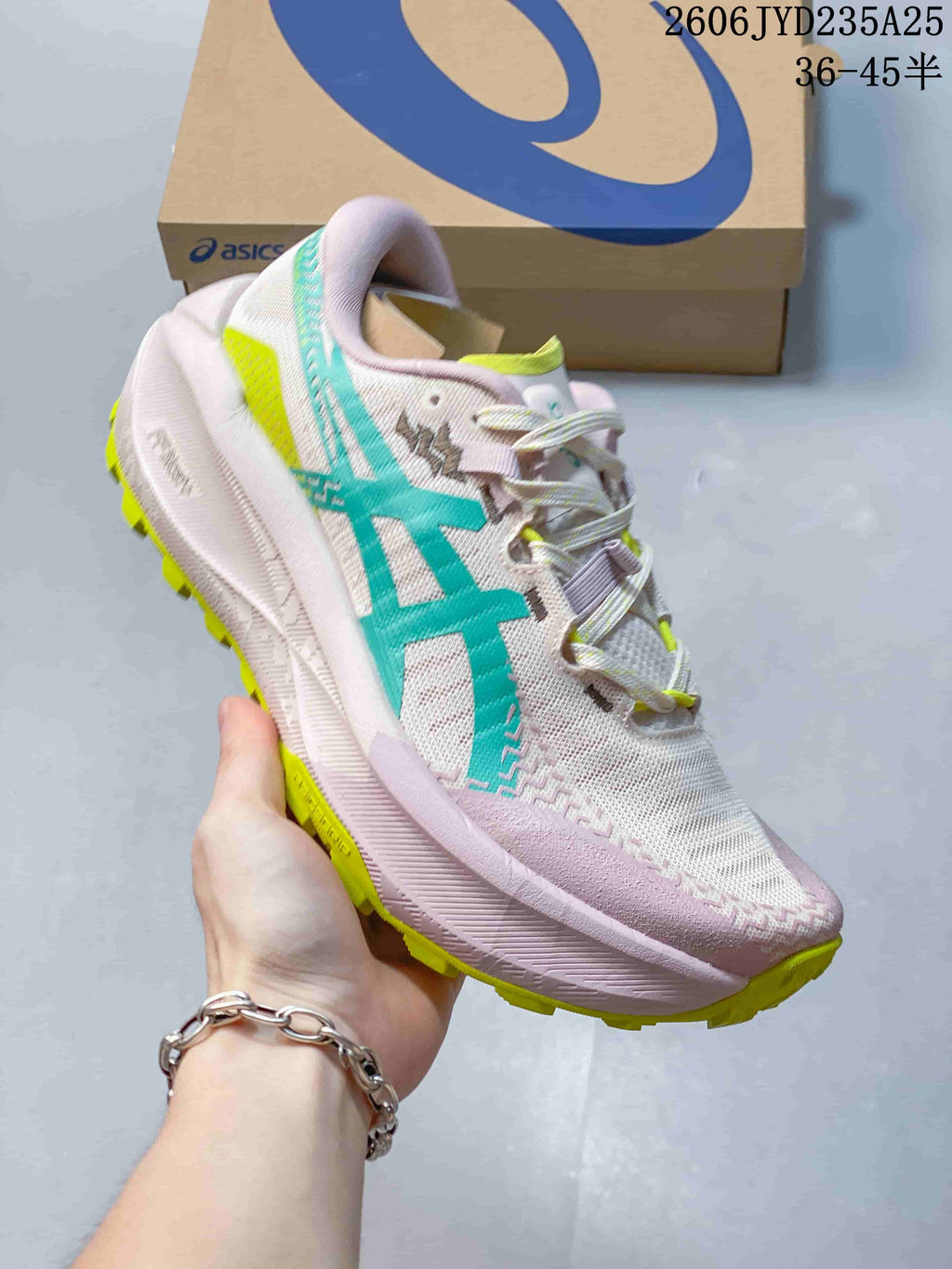 Side view of a light pink ASICS GEL-TRABUCO MAX 5 shoe with teal and yellow details and a lugged outsole.