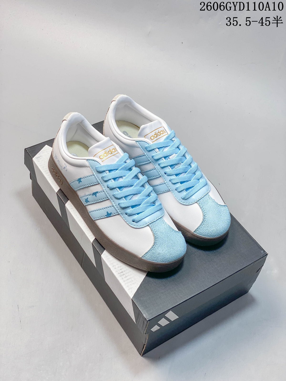 Pair of white and light-blue adidas VL Court Classic DIY sneakers with star details and brown outsoles