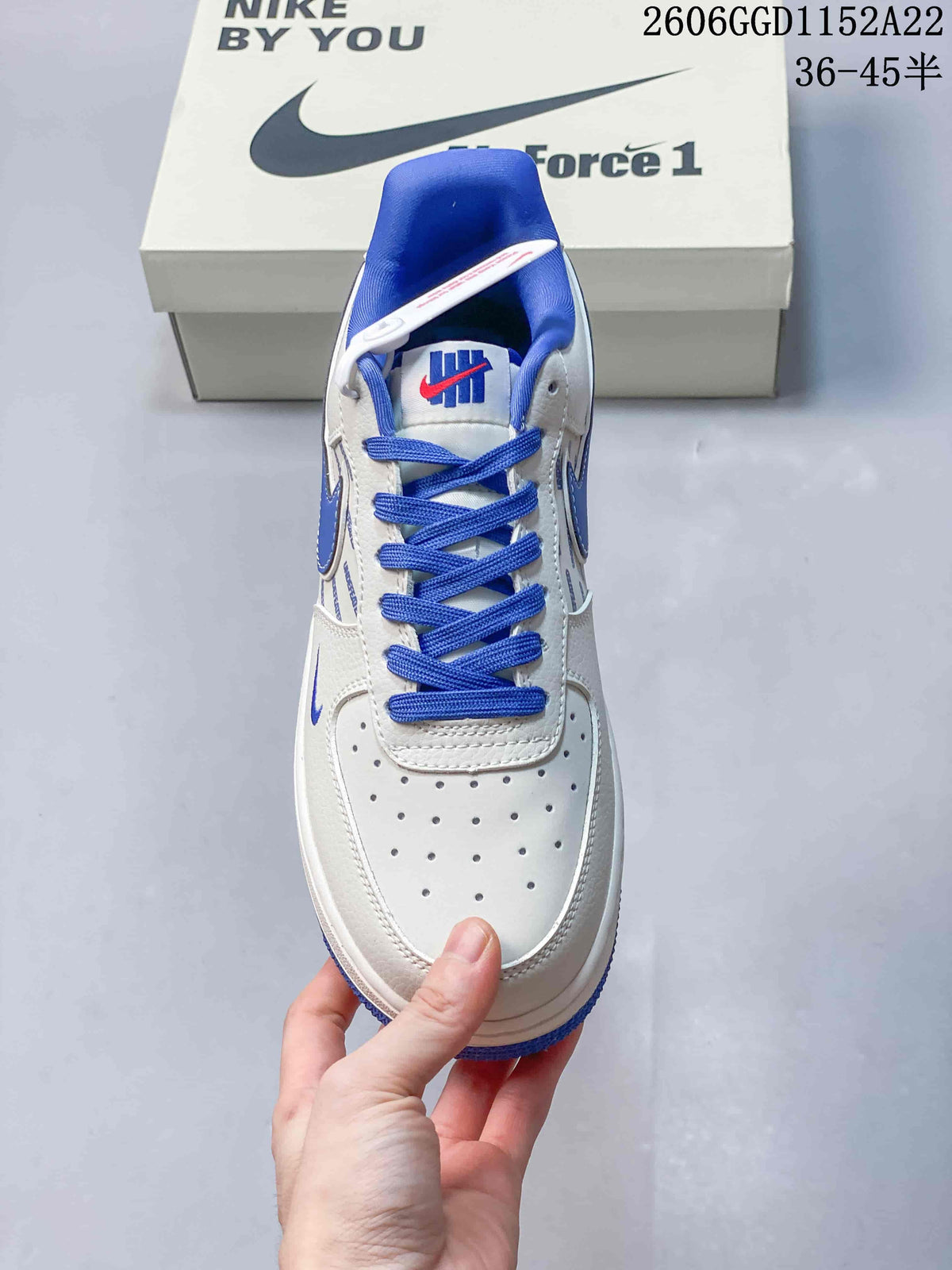 Top view of a white Air Force 1 sneaker with blue laces and toe perforations