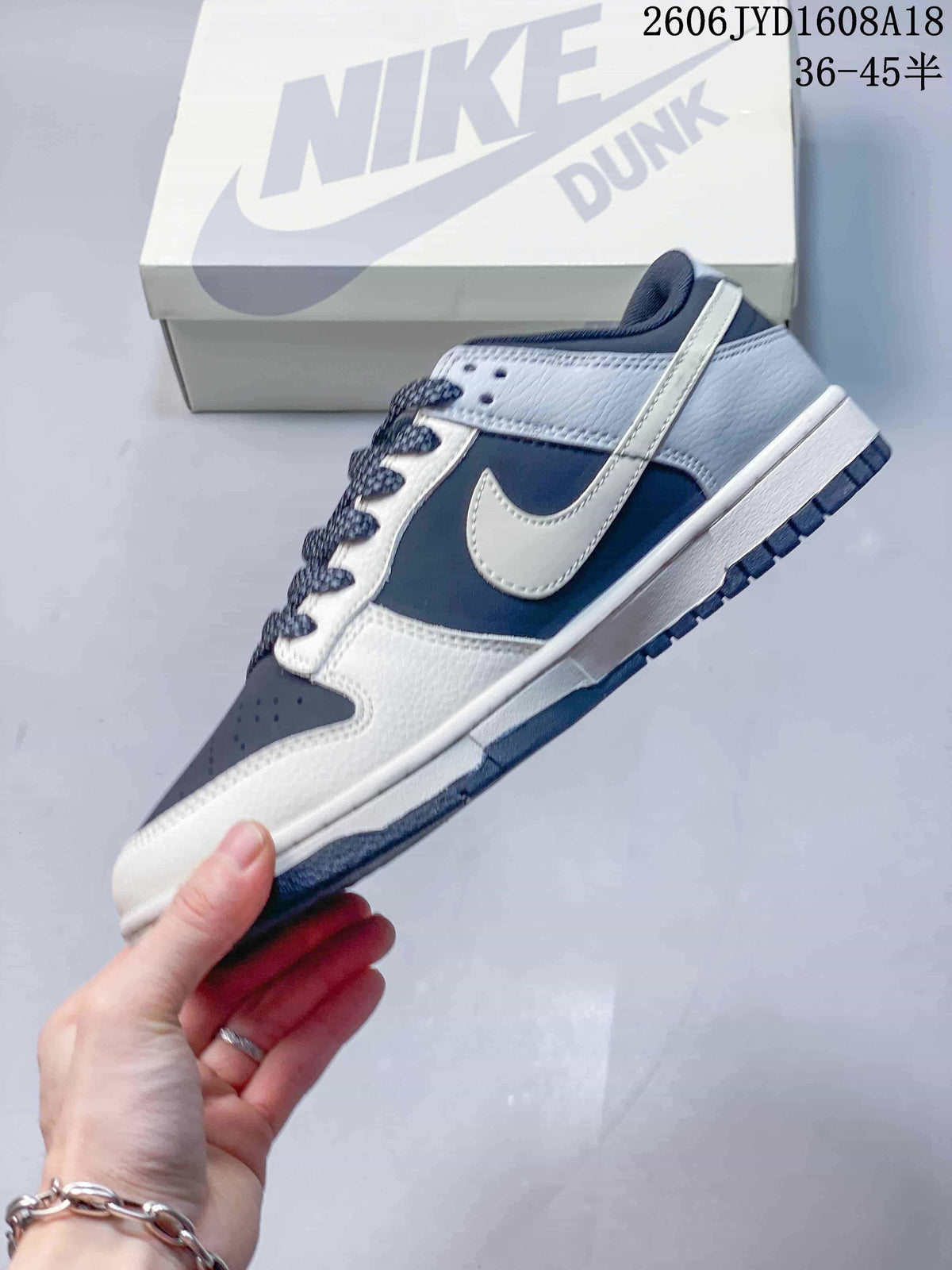 Side profile of a navy, grey, and off-white low-top sneaker with a contrast Swoosh
