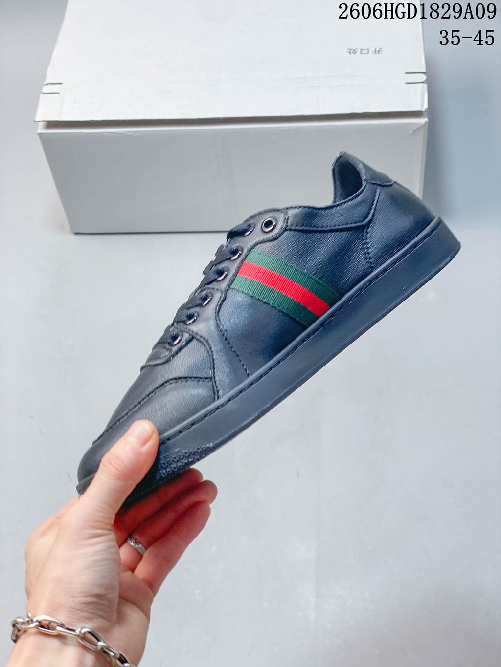 Side view of a navy lace-up sneaker with green-and-red striped detailing.