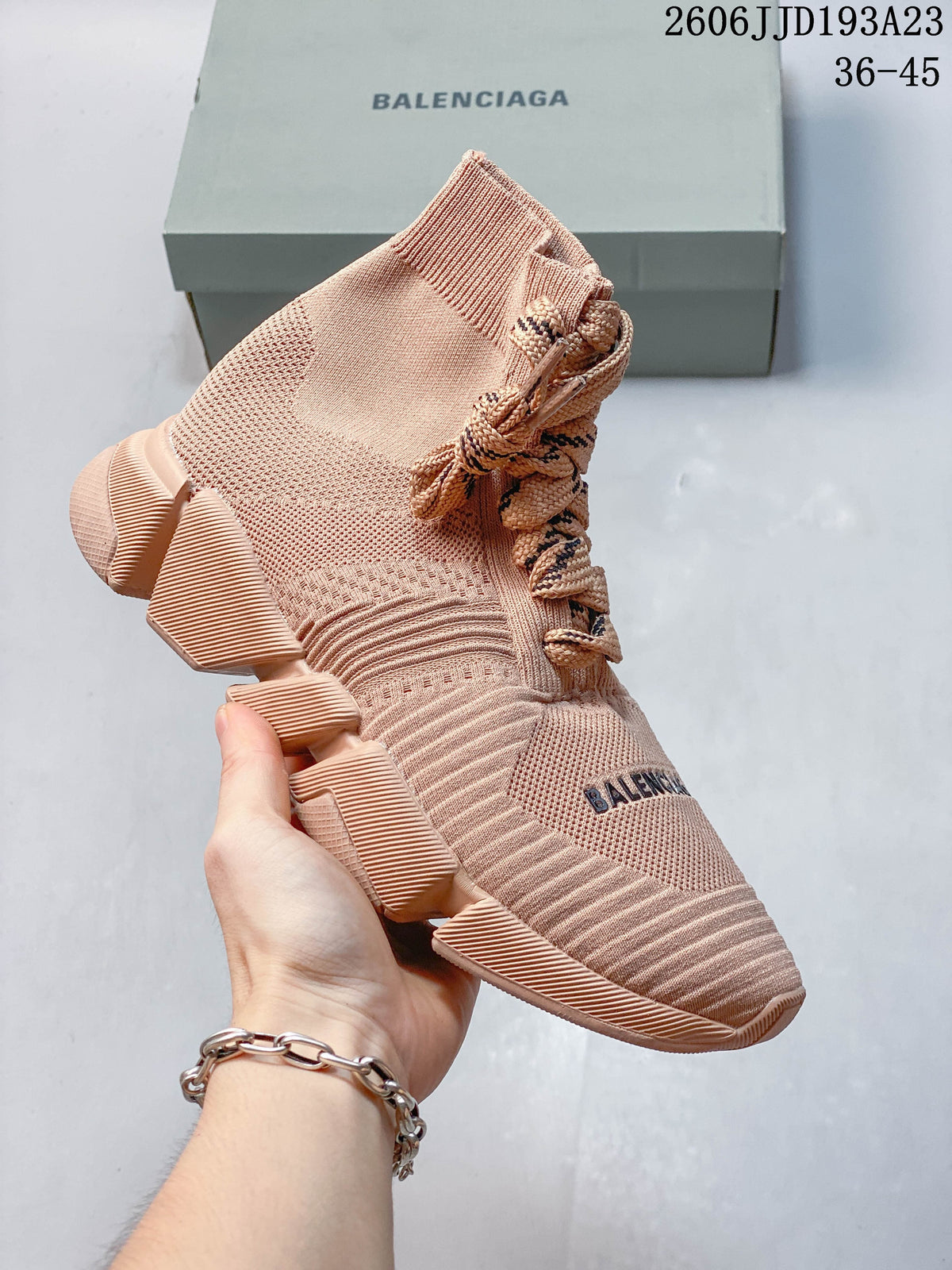 A blush pink high-top Balenciaga sneaker with patterned laces and a sculpted segmented sole.