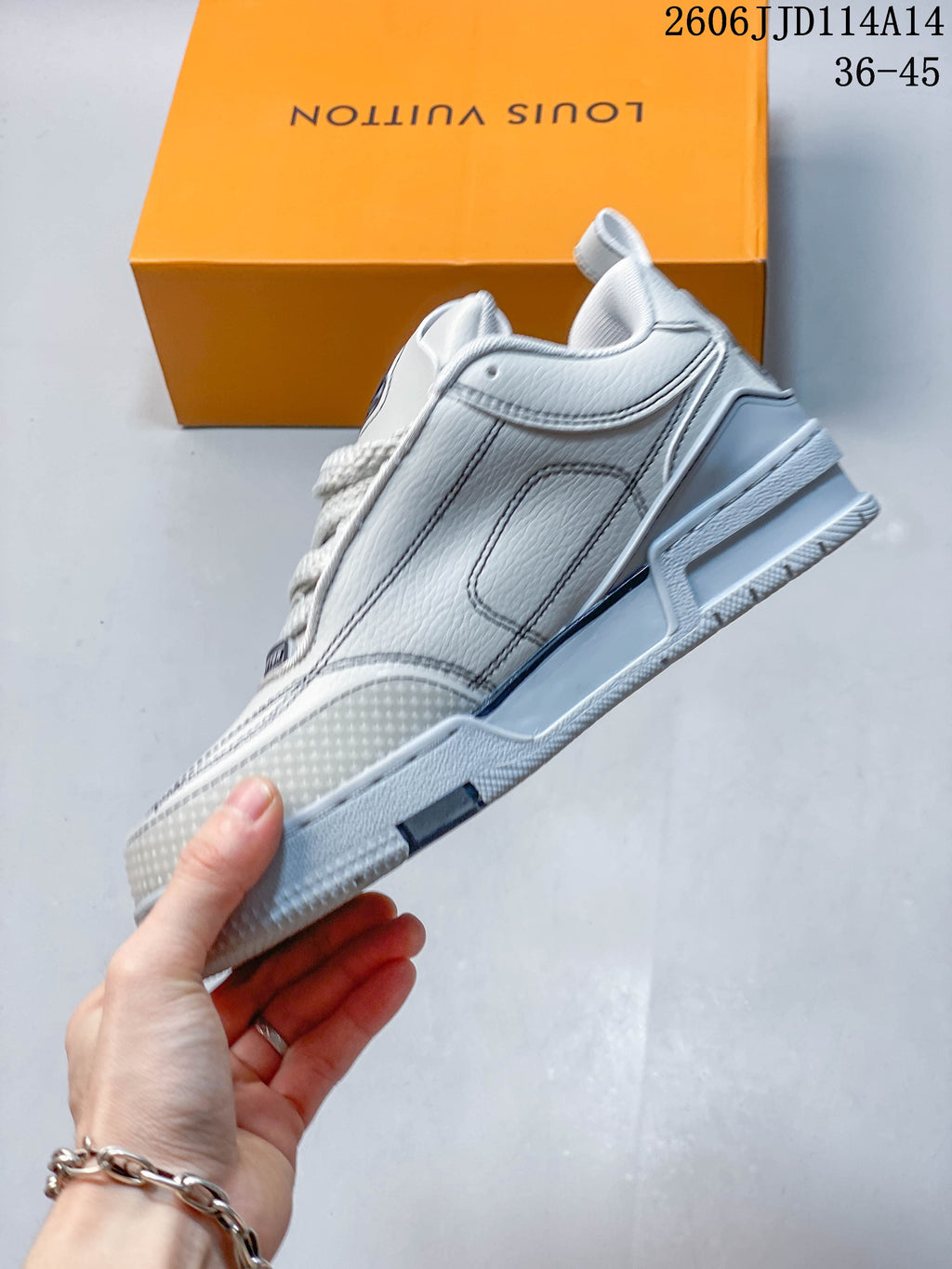 Side profile showing layered panels, contrast stitching, and the thick sole of a white and gray Trainer sneaker.