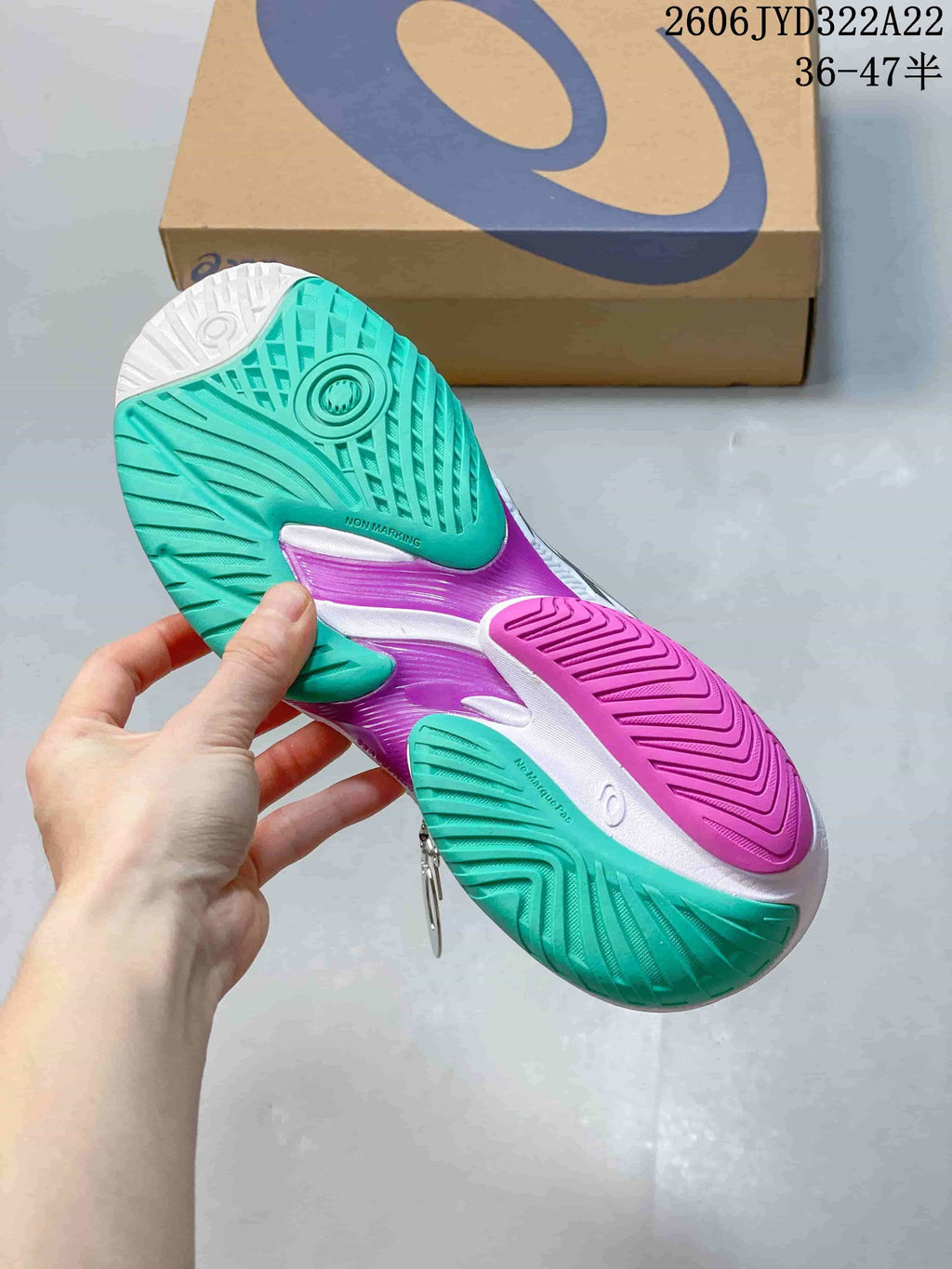 Close-up of the teal, magenta, and white outsole of an ASICS tennis shoe.