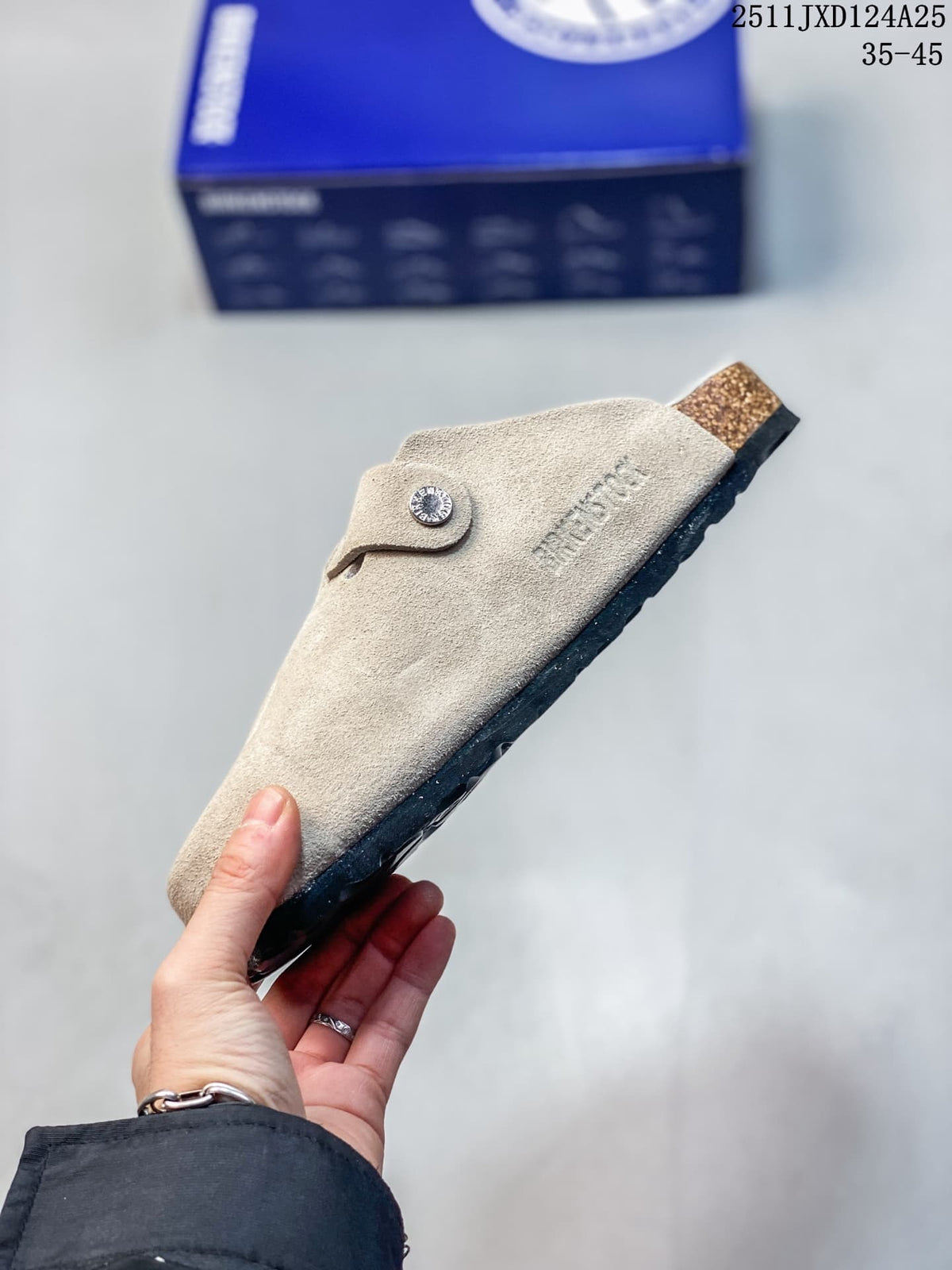 Side profile of a taupe clog showing its closed upper, buckle detail and cork-look midsole