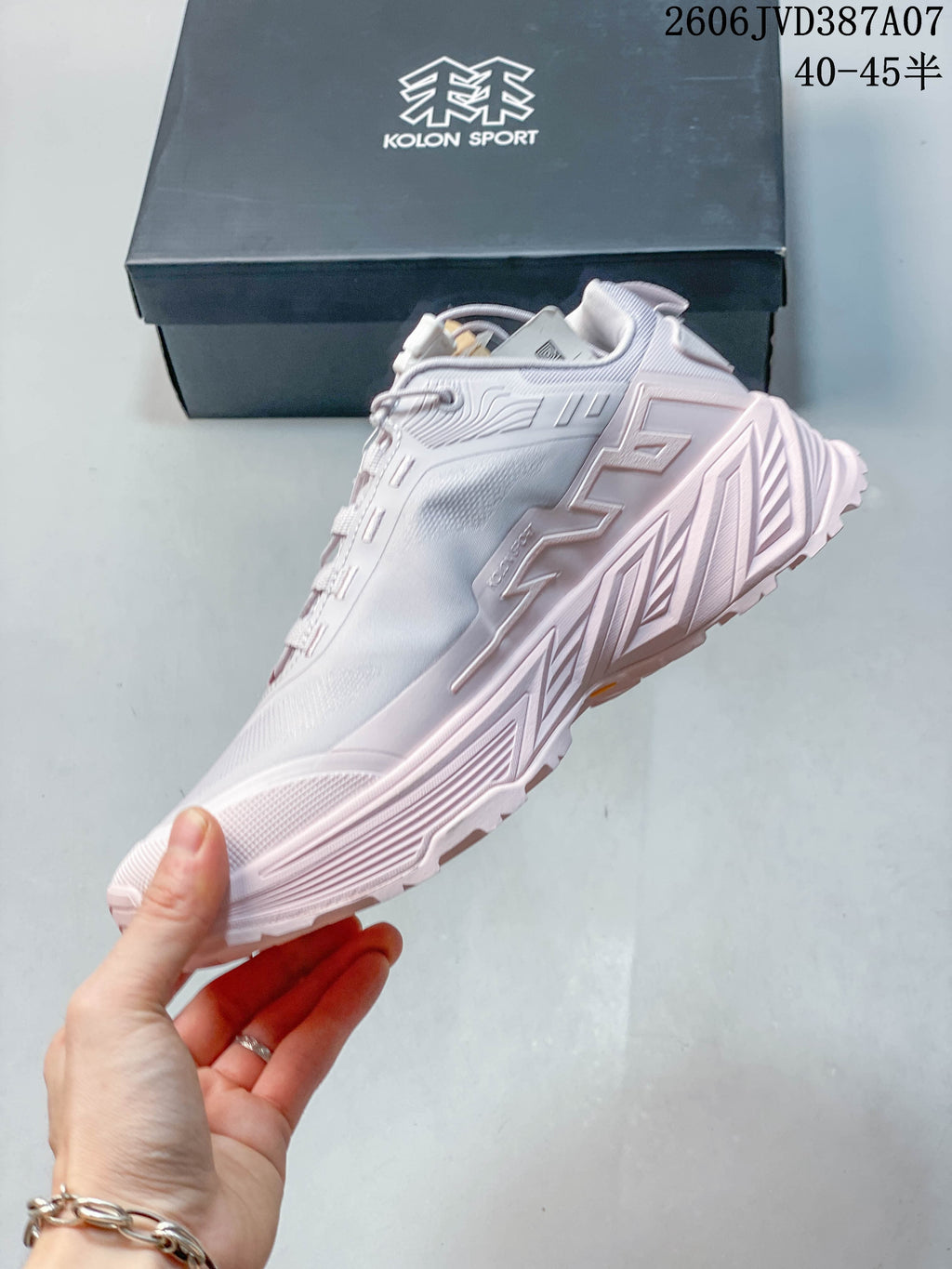 Side profile of a pale gray and pink Kolon Sport sneaker