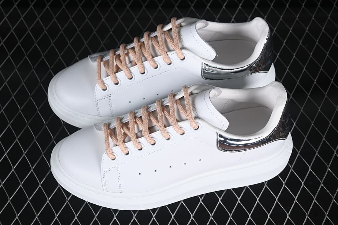 Pair of white low-top sneakers with reflective heel panels