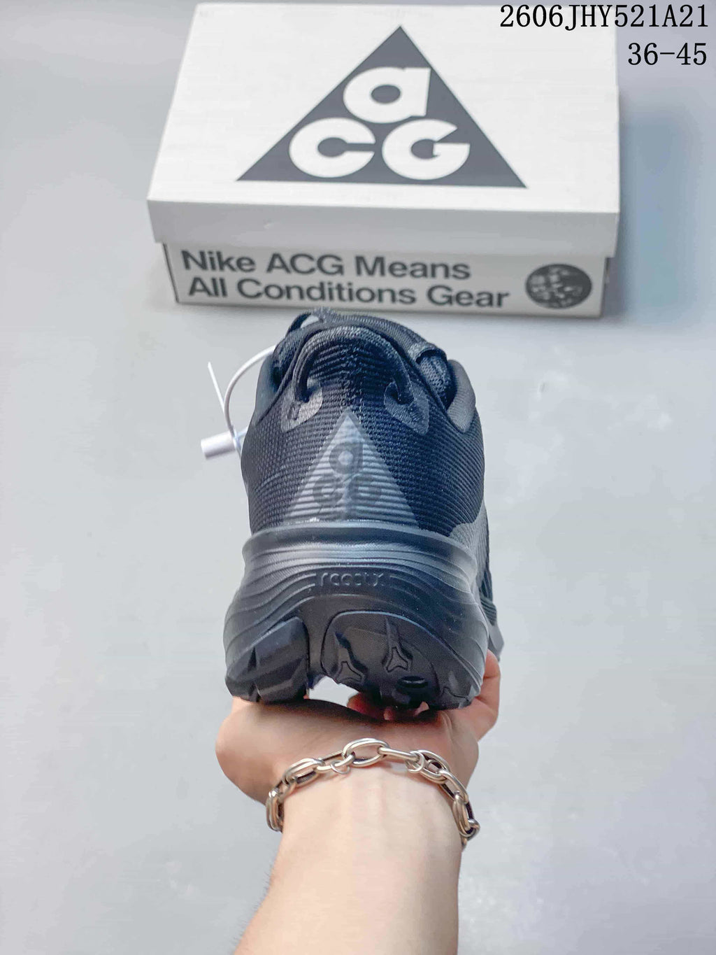 Rear view of a dark gray shoe with ACG details and the product box behind it.