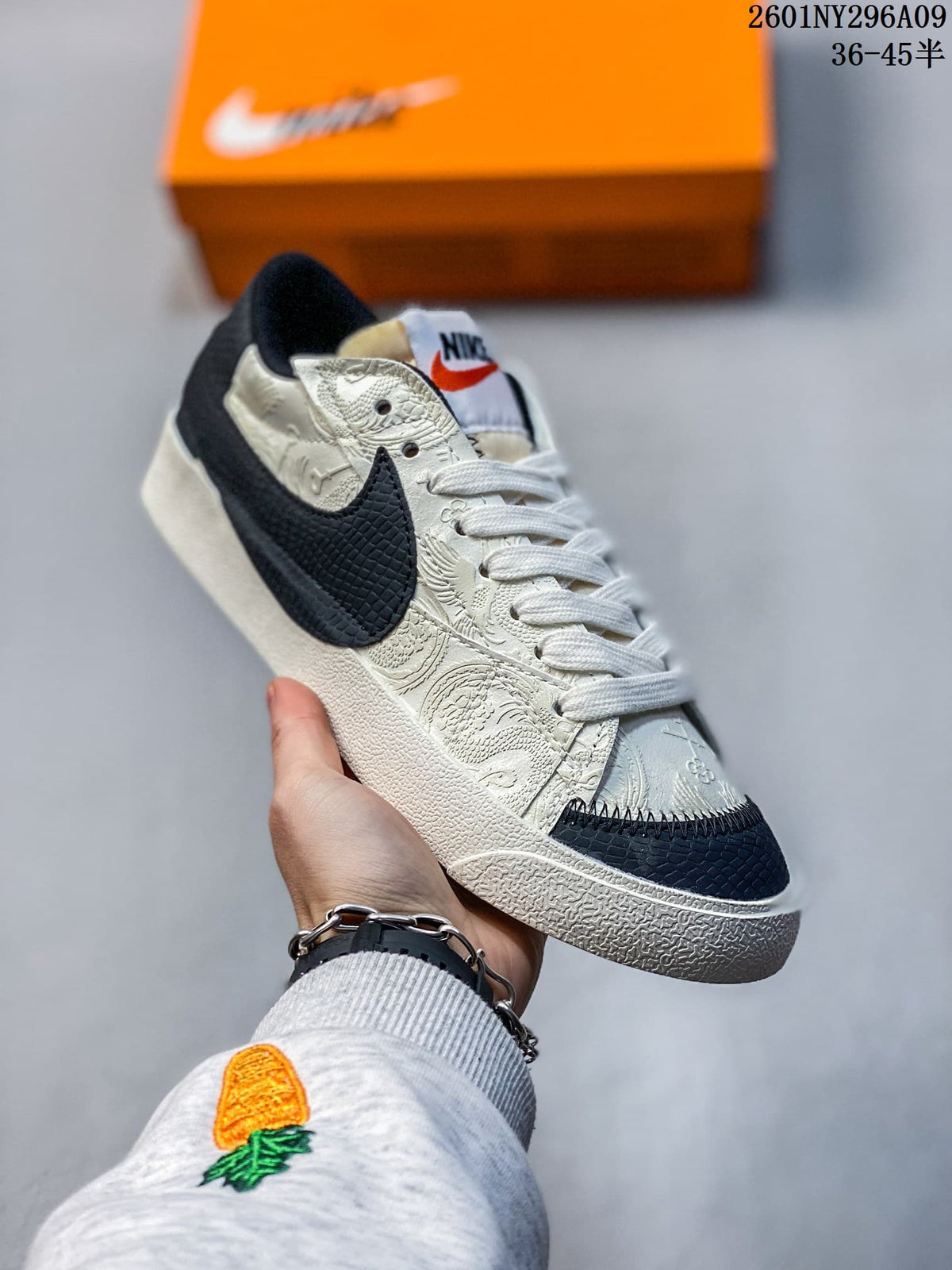 Cream and black Nike Blazer Low '77 Jumbo sneaker with decorative patterned panels and a dark Swoosh.