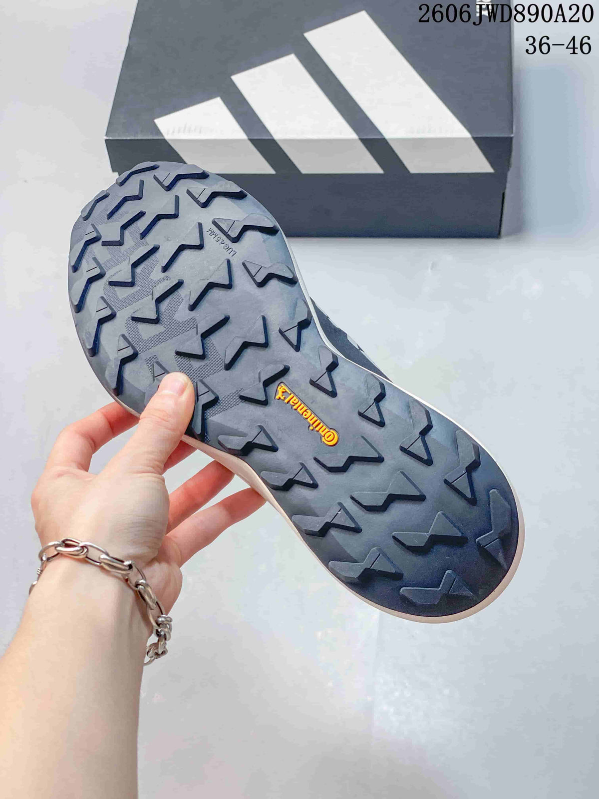 Close-up of the shoe's lugged outsole with an adidas box in the background.