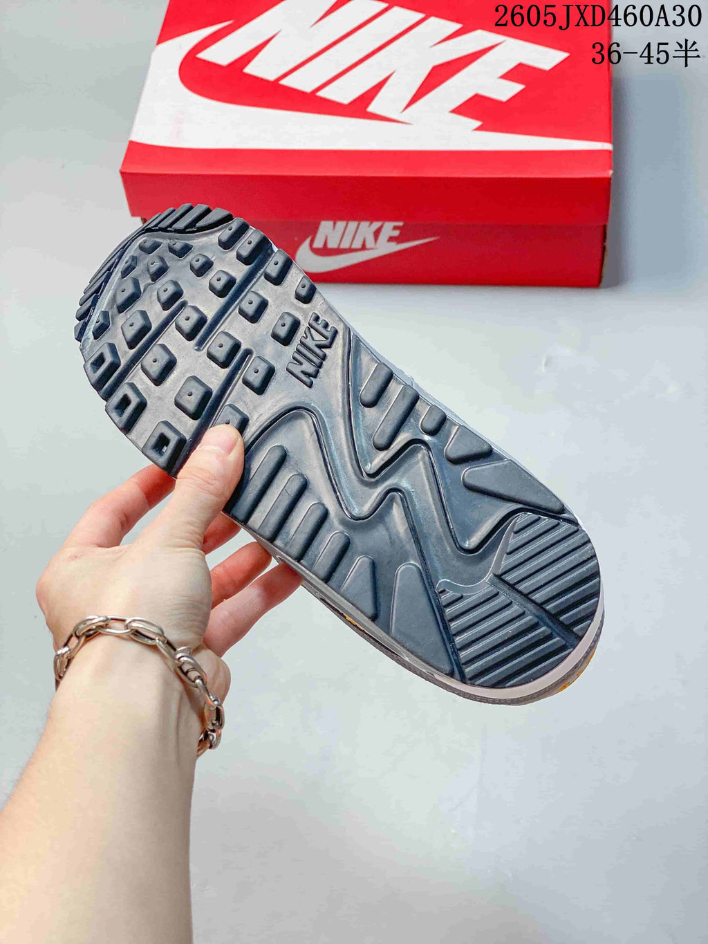 Close-up of the dark patterned outsole on the grey Nike Air Max 90 sneaker.