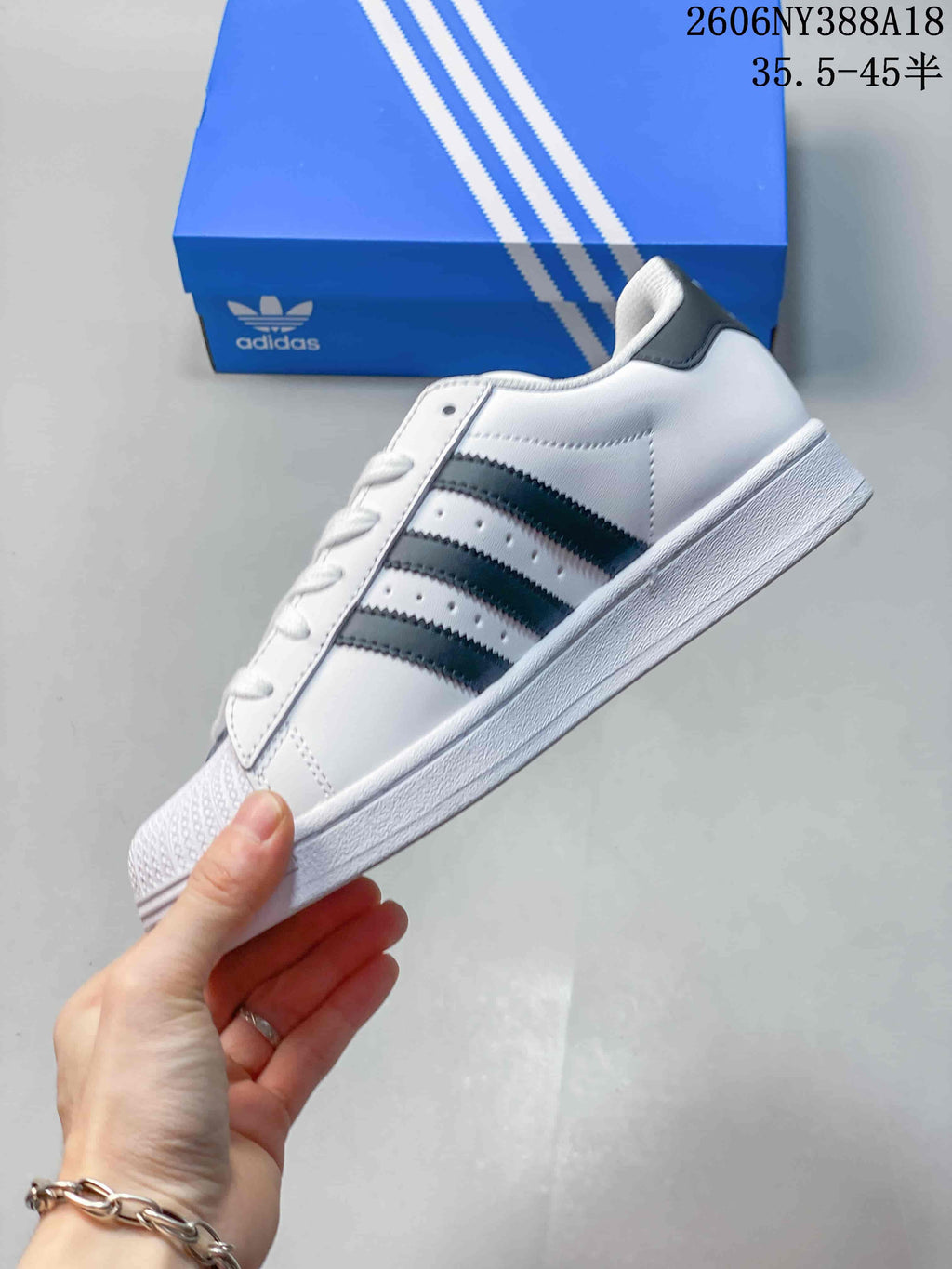 Side view of the white low-top sneaker with dark stripes and shell-style toe.