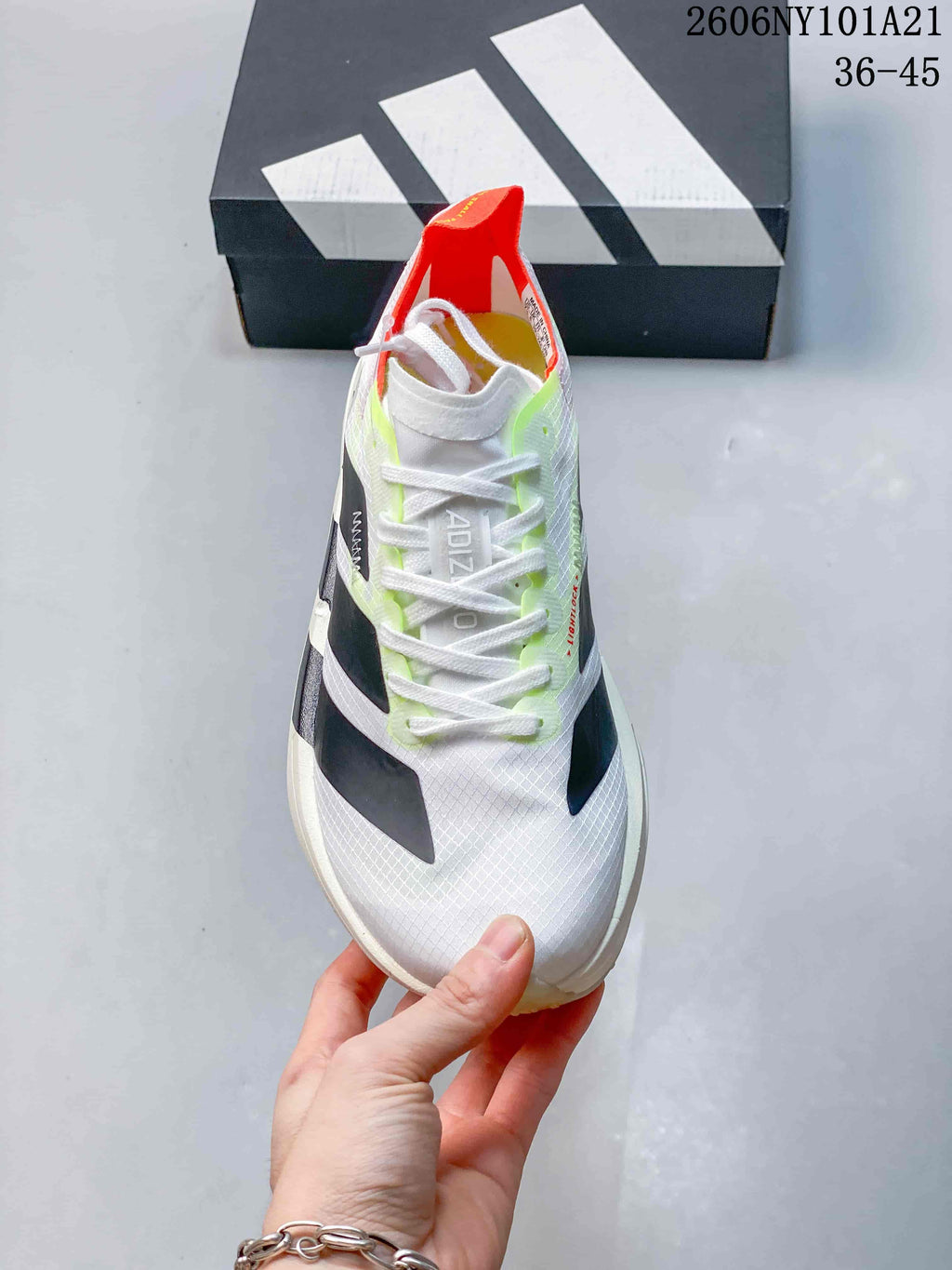 Front view of a white lace-up Adidas shoe with dark stripes and neon accents.