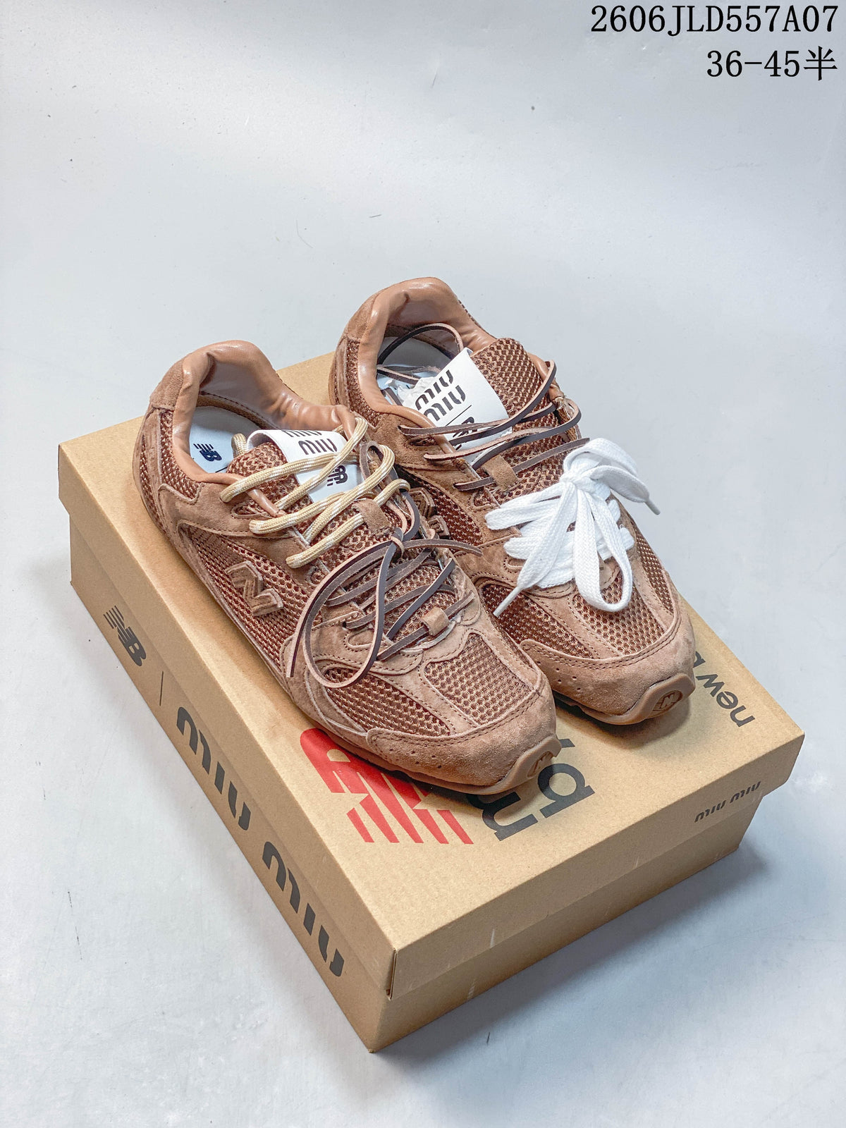Pair of brown-toned New Balance 530 SL sneakers on a branded box, showing contrasting lace details.