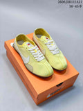 Pair of pale yellow Nike low-top sneakers with white laces and Swoosh accents, shown on an orange shoe box.