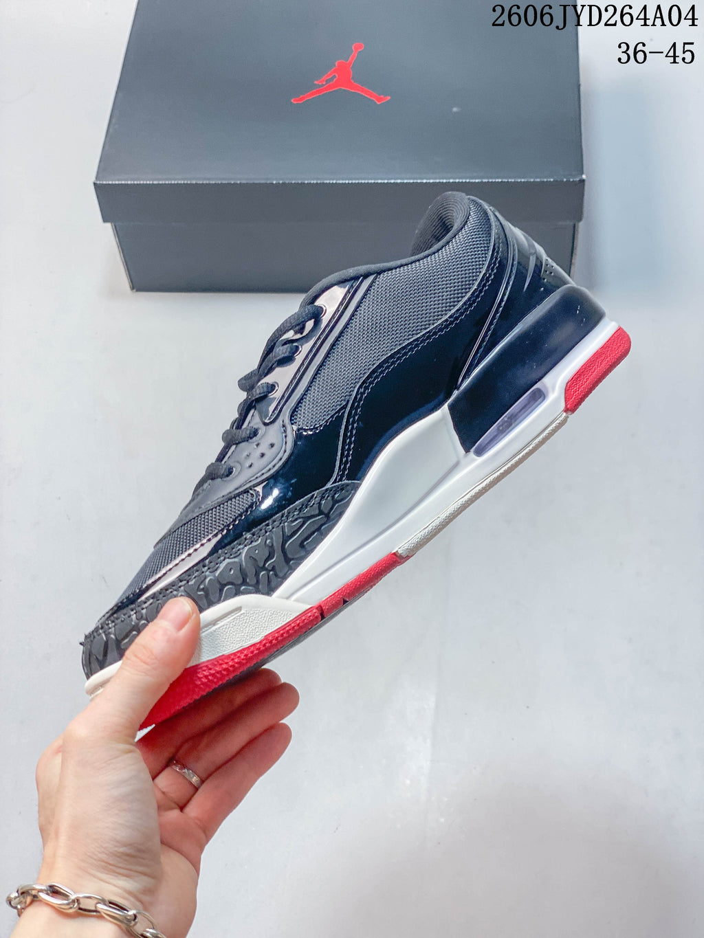 Side view of the dark sneaker showing mesh-look panels, glossy overlays, and red outsole accents