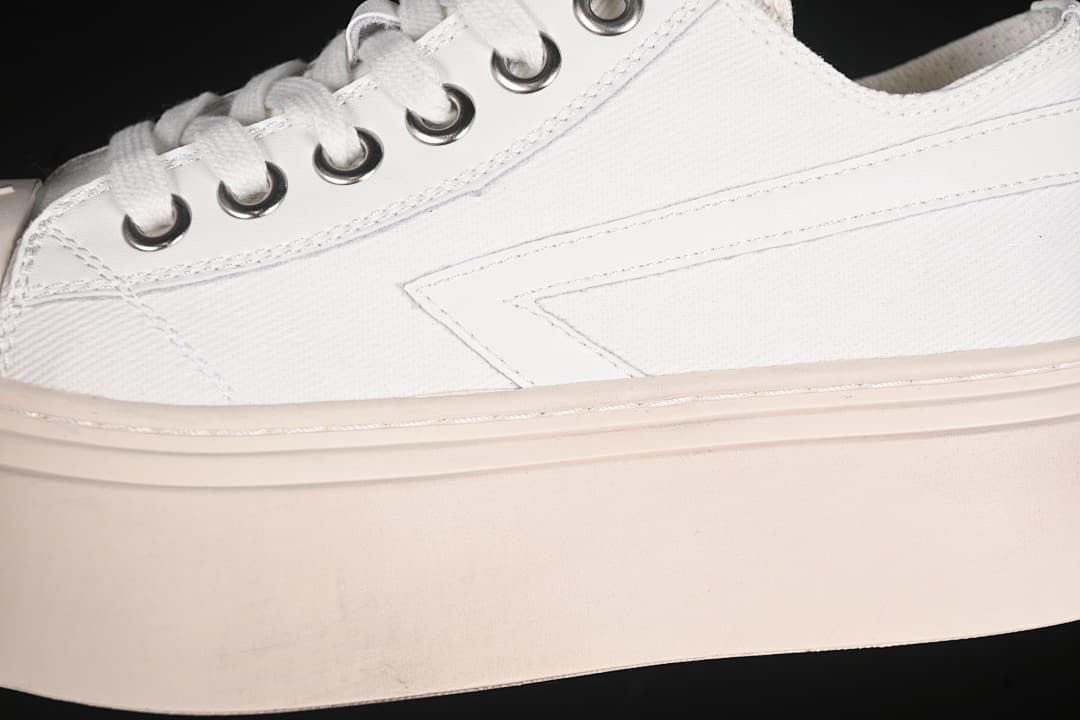 Side close-up showing the white upper, metal eyelets, laces, and thick pale sole.