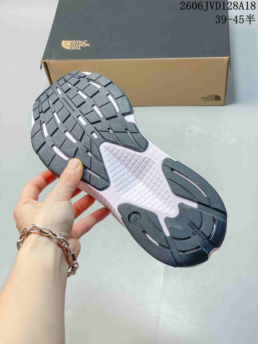 Close-up of the dark patterned outsole on a white The North Face running shoe.