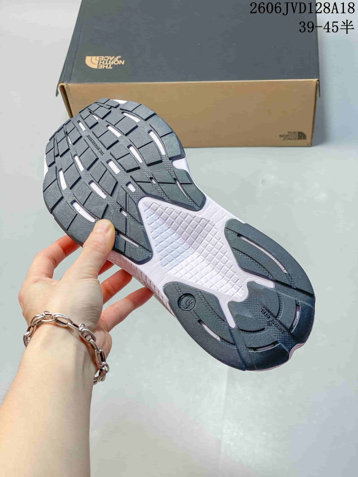 Close-up of the dark patterned outsole on a white The North Face running shoe.