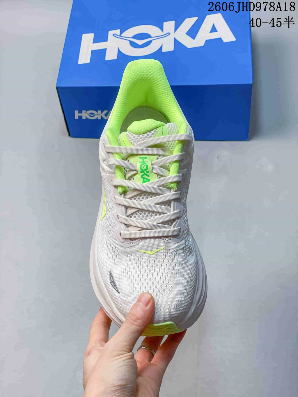 Front view of a white Bondi 9 running shoe with neon-green lining and lace details