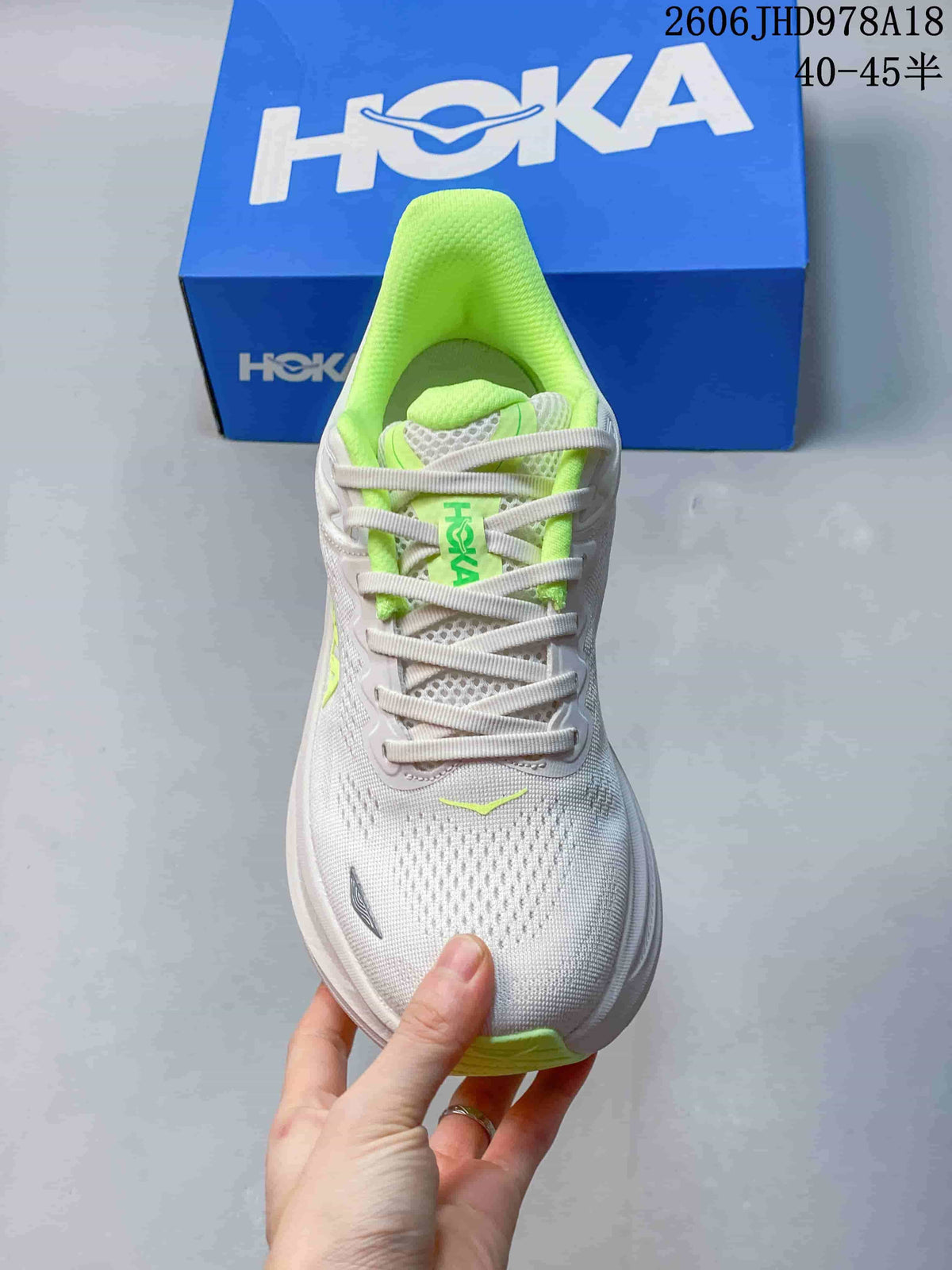 Front view of a white Bondi 9 running shoe with neon-green lining and lace details