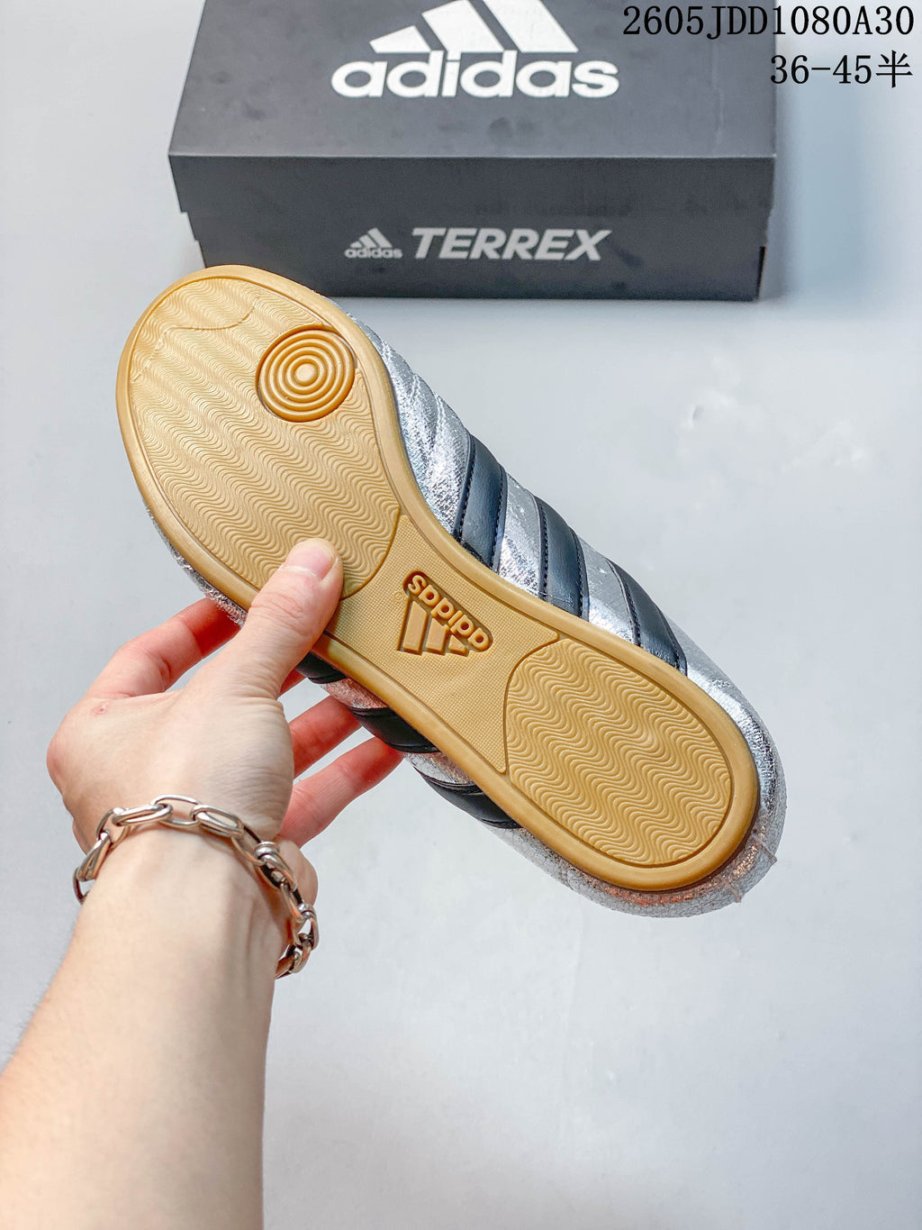 Underside of a silver shoe showing a gum-colored patterned outsole