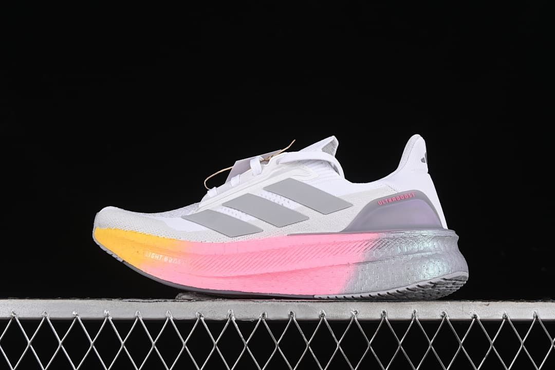 Side view of white Adidas Ultraboost 5X shoes with grey stripes and a pink and yellow midsole