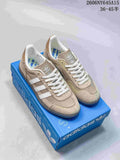 Pair of taupe Adidas Handball Spezial sneakers with white stripes and laces, shown on a blue shoe box.