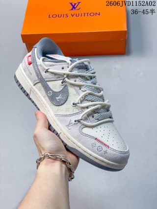 Angled side view of the gray and white sneaker showing patterned panels, perforated toe box, swoosh, and red detail.