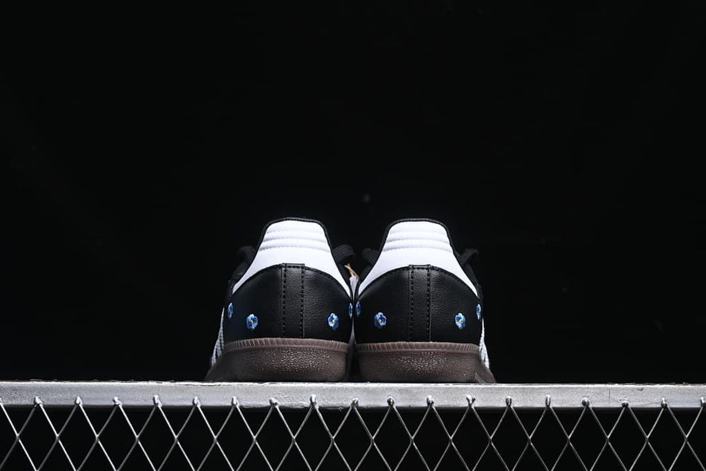 Rear view of both shoes showing white heel panels and embroidered flowers
