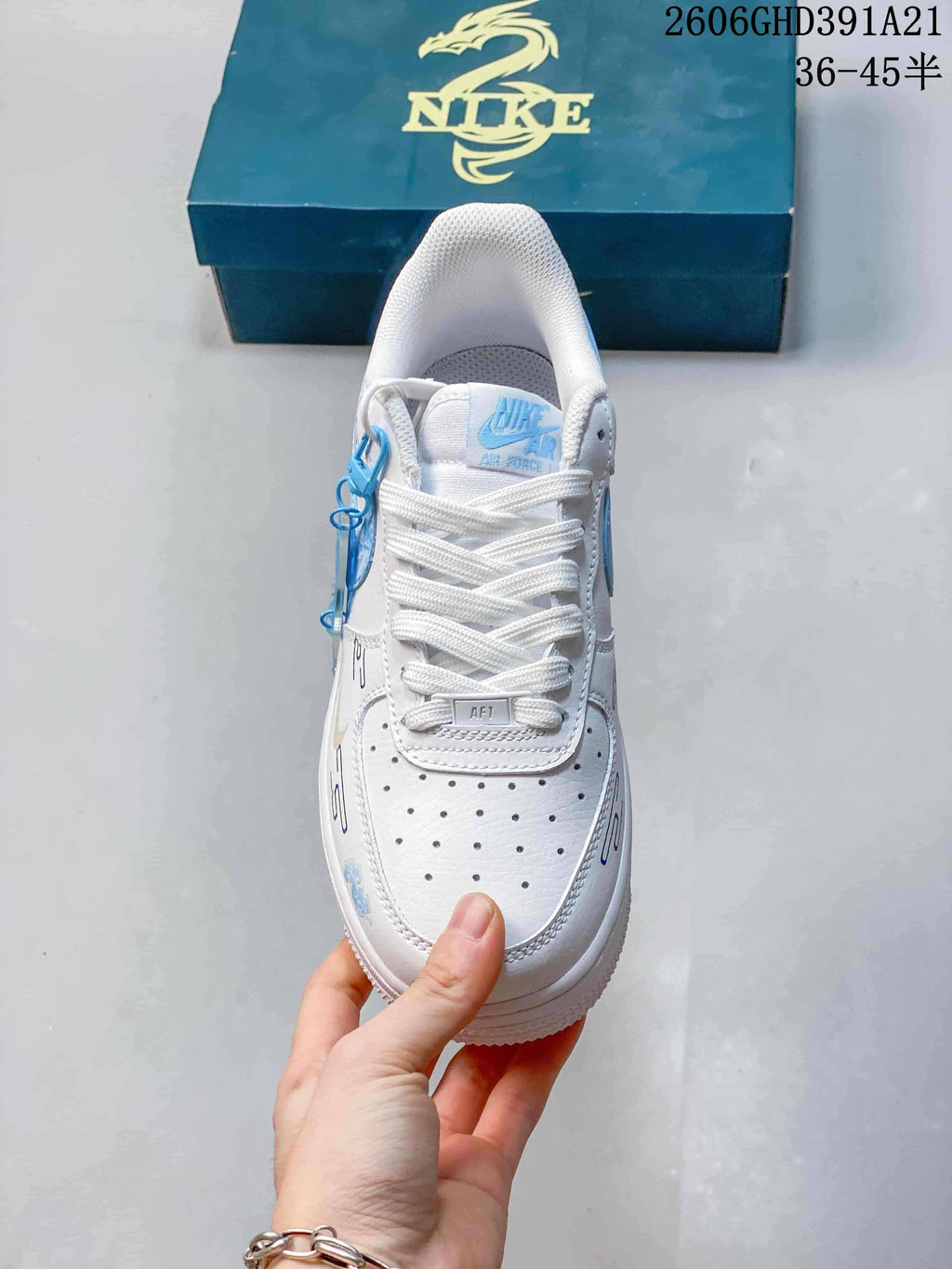 Top view of the sneaker showing white laces, a perforated toe box and a blue lace accessory.