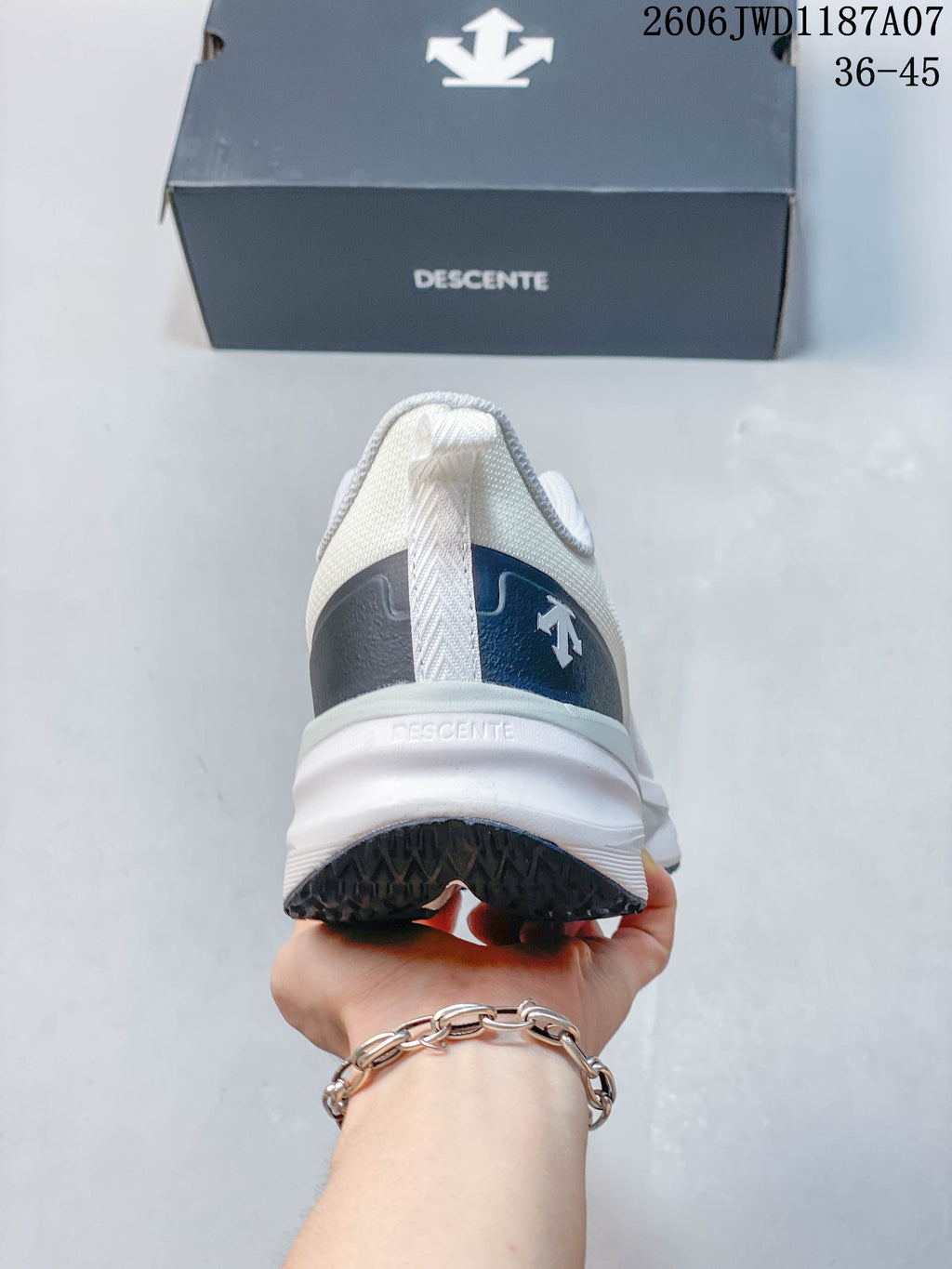 Rear view of the white DESCENTE shoe showing the heel and outsole.