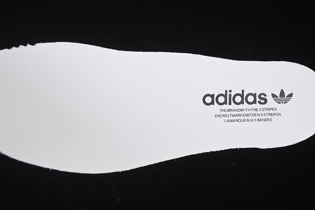 White shoe-shaped cutout with adidas branding against a black background