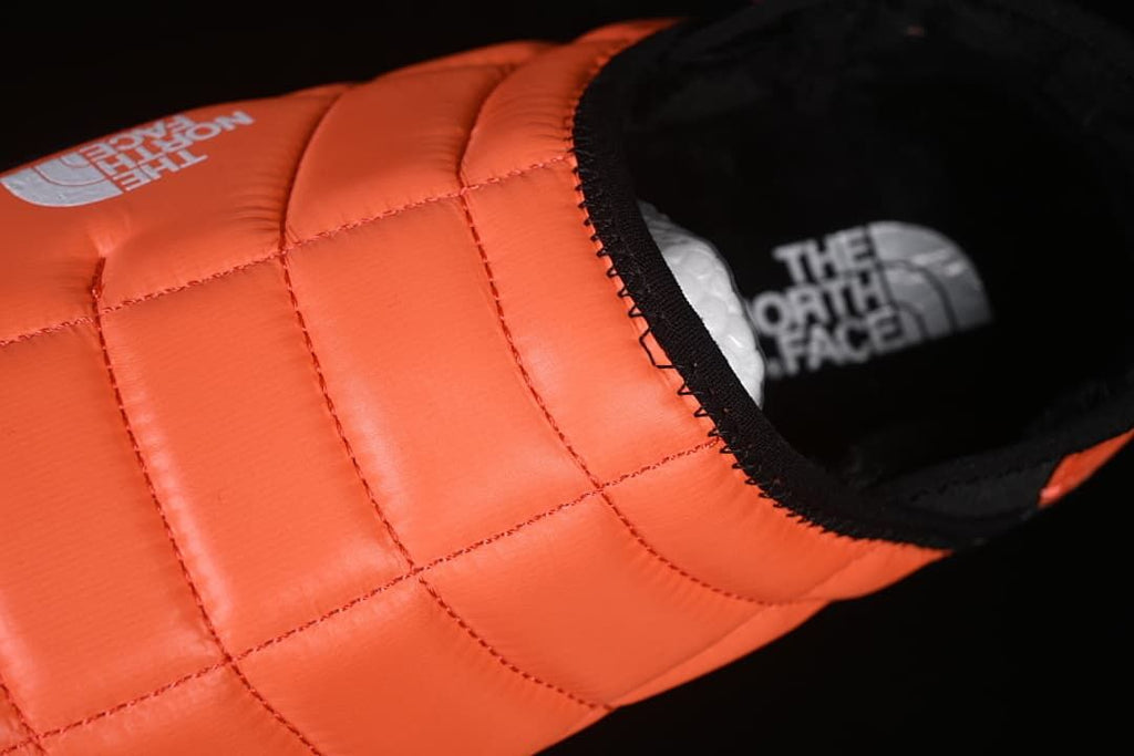 Top angle showing the orange quilted upper and black footbed