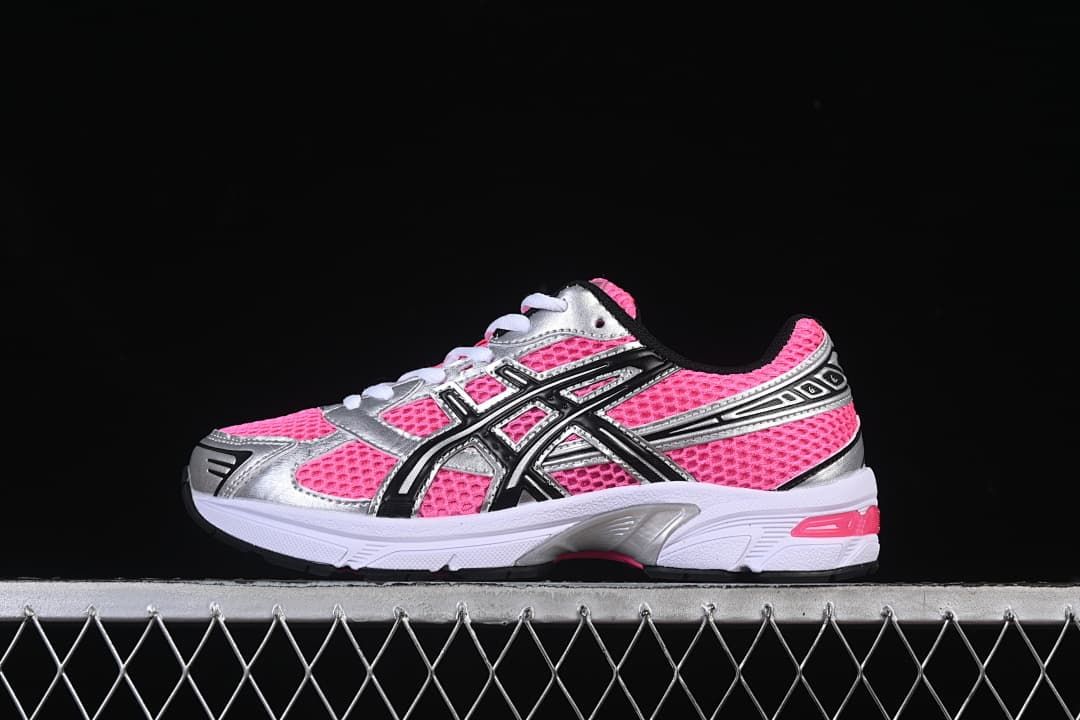 Side profile of a pink, silver, and black sneaker against a black background.