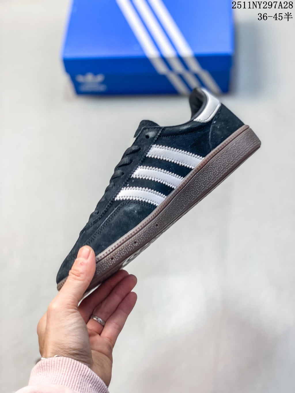 Side view of a dark navy Adidas Handball Spezial sneaker with light side stripes and a brown outsole.