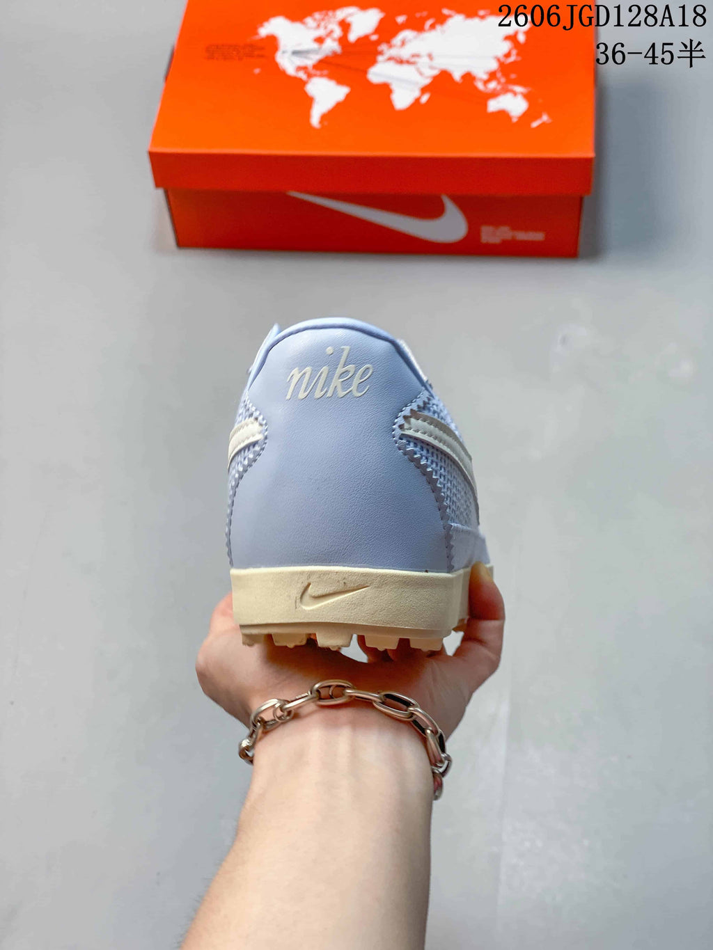 Heel view of the light blue sneaker with pale branding and cream-colored sole