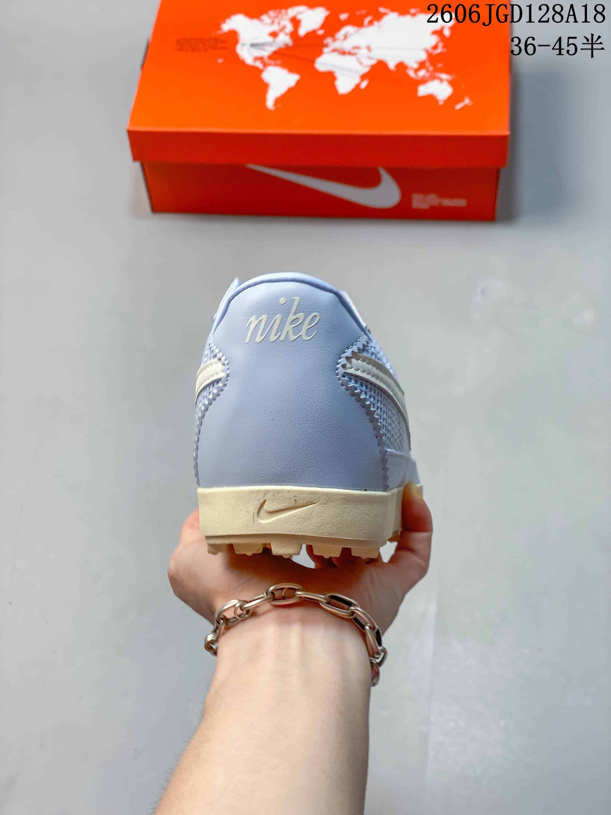 Heel view of the light blue sneaker with pale branding and cream-colored sole