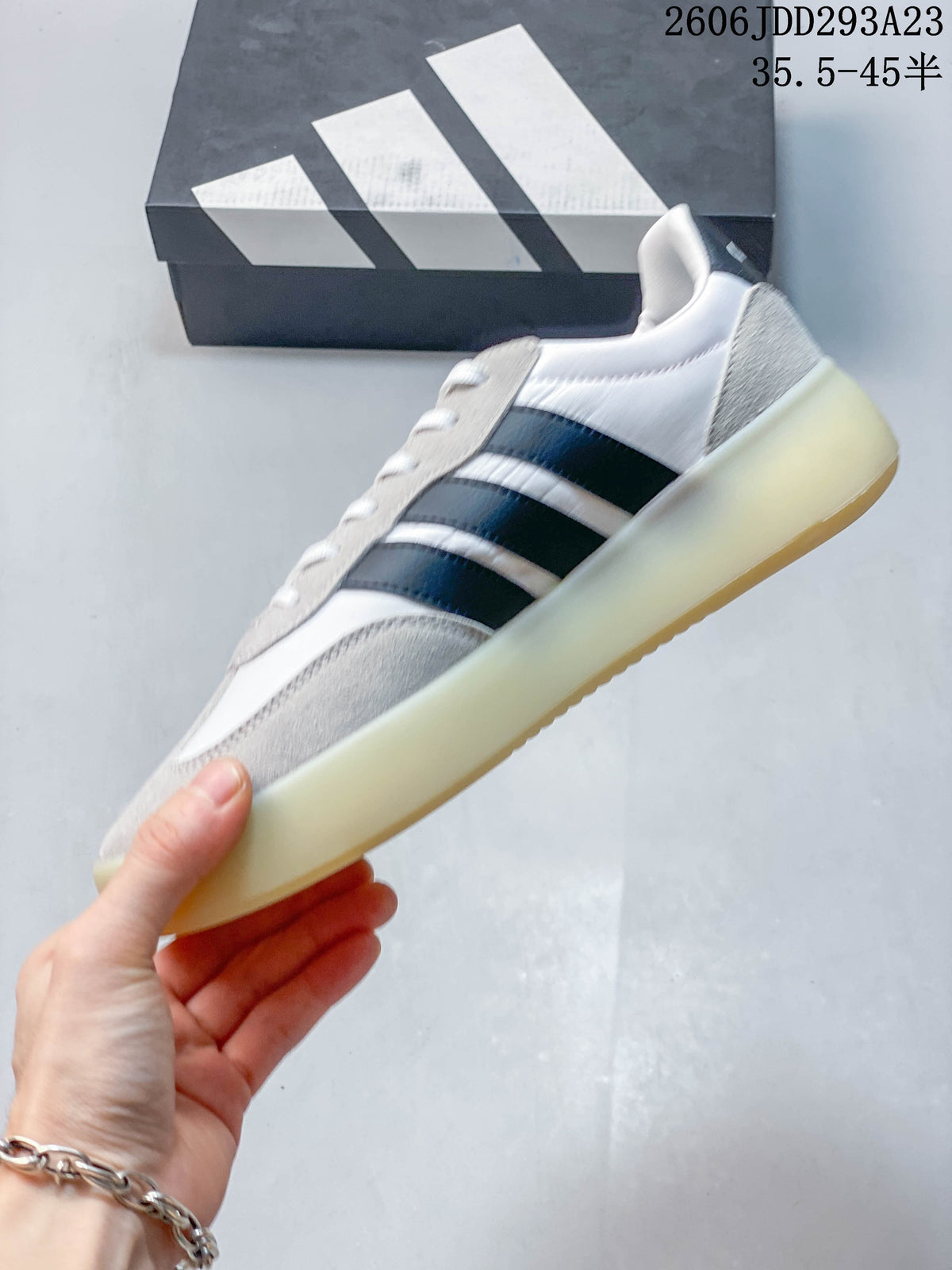 Side view of the white sneaker with gray overlays and navy stripes